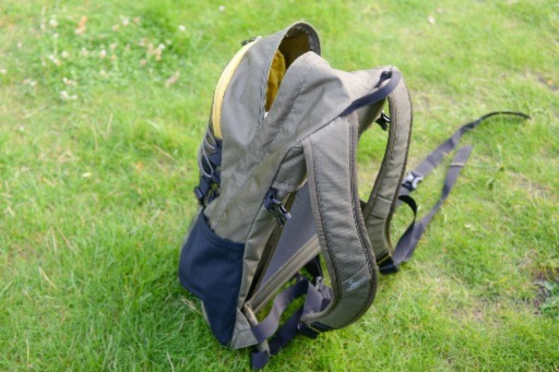 a tan and green north face backpack sitting in the grass